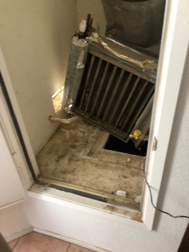 An air conditioning unit sits on a dirty floor.