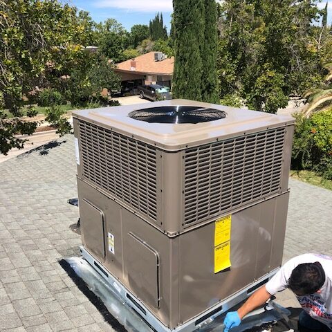 An air conditioner machine with worker at the roof
